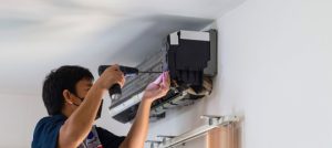 Technician performing HVAC maintenance on a wall-mounted air conditioning unit, ensuring system efficiency and safety.