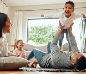 Family enjoying quality time indoors, with parents playing with children, highlighting the importance of a comfortable home environment for HVAC discussions.