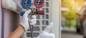 HVAC technician using pressure gauge on air conditioning unit, emphasizing energy efficiency and maintenance practices.