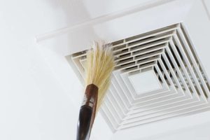 Brush cleaning an air duct vent, highlighting the importance of air duct maintenance and cleaning.