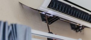 Technician servicing an HVAC air conditioning unit, highlighting maintenance and compliance with HVAC regulations.