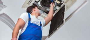 HVAC technician inspecting indoor air conditioning unit for maintenance and air quality improvement.