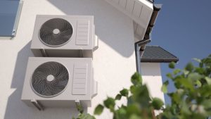 Dual outdoor HVAC units mounted on a residential wall, illustrating a dual fuel system for efficient heating and cooling.