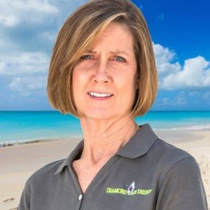 Woman in a Diamond Air Design polo shirt, standing on a beach with turquoise water and clouds in the background, representing local HVAC services.